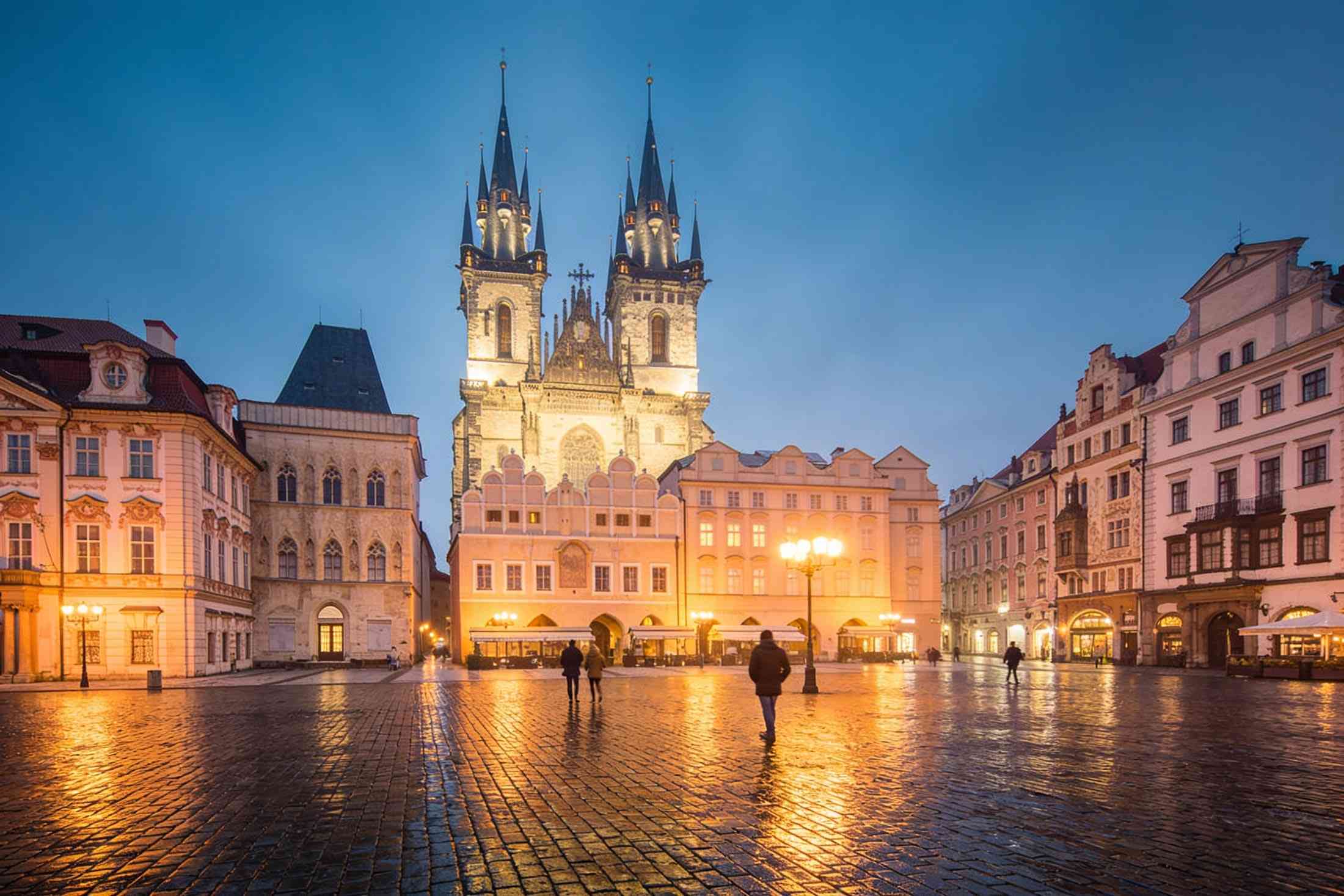 Old Town Square at blue hour, Týn Church lit up and the wet cobbles shining under the lamps